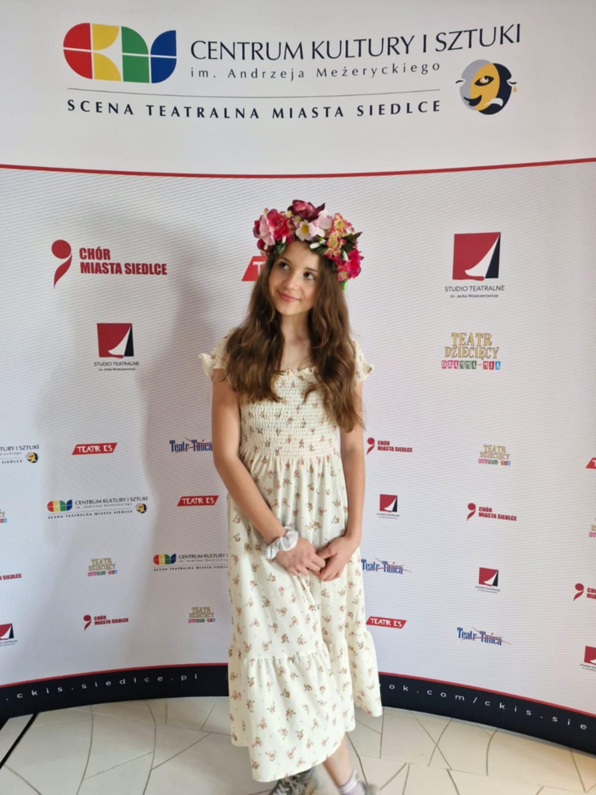 Ania ubrana w letnią sukienkę stoi przy ściance podczas Festiwalu Piosenki o Zdrowiu.